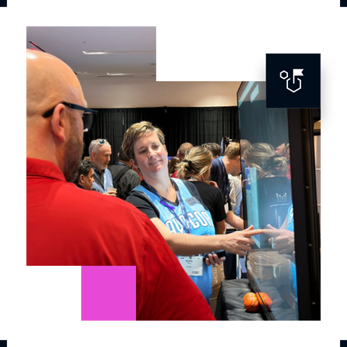 Woman in DUOCON shirt and man using large touchscreen display at tech event.
