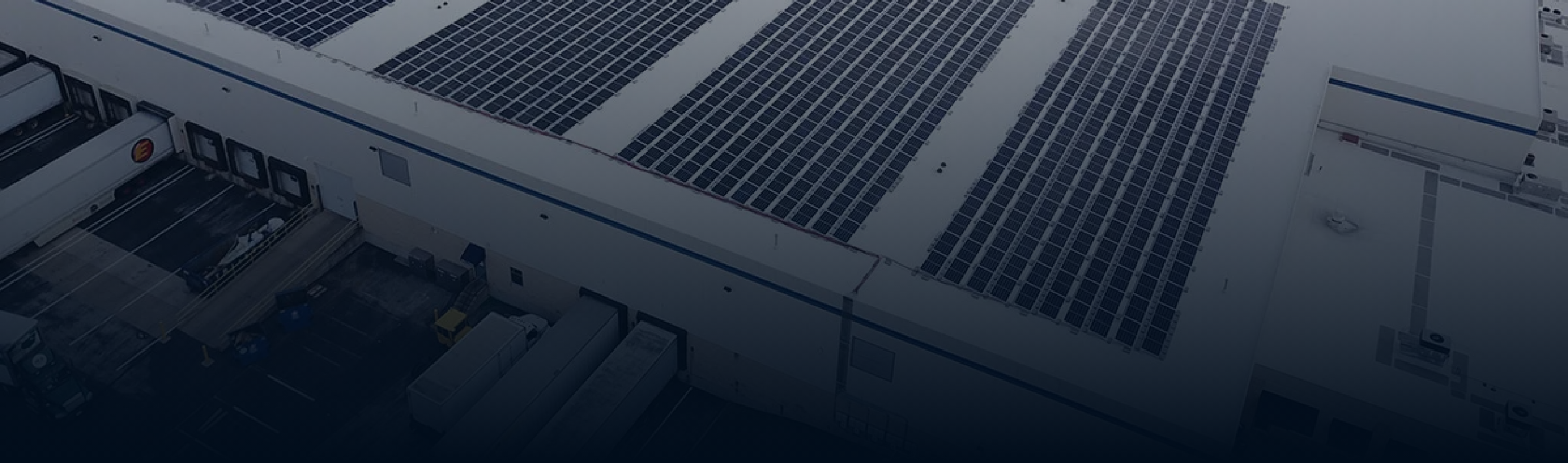 Industrial rooftop covered with rows of solar panels above loading docks.