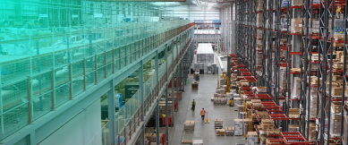 Modern warehouse with tall shelving, mezzanine, and workers in safety vests.