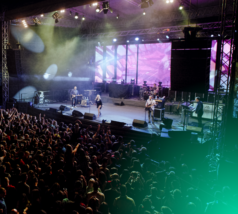 Band with female singer performing on stage before large crowd.
