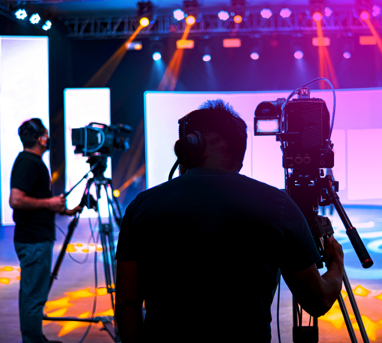 Camera operators filming in studio with colorful LED screens.