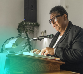 Woman in glasses speaking at a podium with a microphone.
